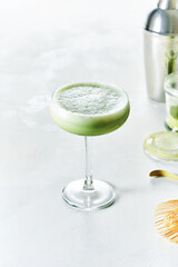 Making Iced Japanese Matcha Latte green tea served in Champagne Saucer glass on white background.