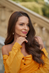 Close-up face portrait of young beautiful caucasian woman with perfect natural make-up and long wavy brunette hair posing outdoors at sunset