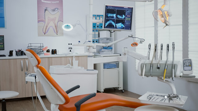 Interior of modern equipped dental orthodontic office with teeth x ray images on monitors, medical dentist stomatology workplace. Zoom in shoot. Empty clinic cabinet for teethcare treatment