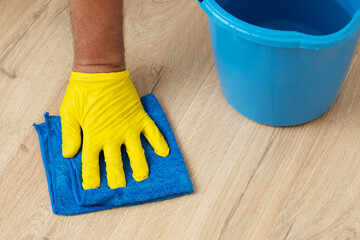 Gloved hand washes a laminate flooring with a wet cloth
