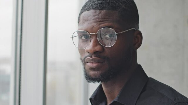 Portrait serious pensive african american business man with glasses ethnic black student afro professional specialist stands in office wears eyeglasses looking at camera with sad male face expression