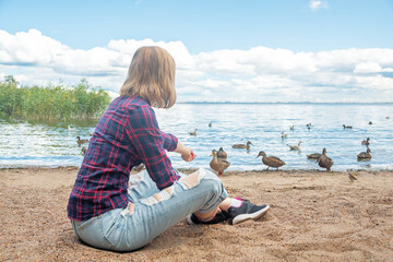 Woman feeds ducks on the Gulf of Finland in the park of the city of Peterhof in Russia