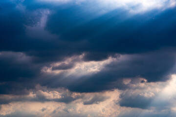 sunbeams shine through dark storm clouds 