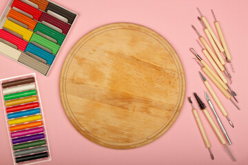 Plasticine modeling tools kit on a pink background. Wooden desk in the classroom for lessons with school children. Sculpting tools for polymer clay. Copy space for text. Close-up. Top view