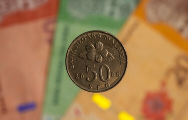 Money, 50 sen coins on blurred background of Ringgit Malaysia banknote, selected focus © JakaSuryanta