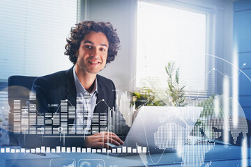 Smiling handsome Hispanic businessman working on laptop to develop trading strategy. Concept of analyzing stock market behavior. Forex bar graphs over the world financial news.