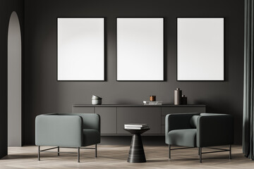 Three posters in the dark grey space with arch and green armchairs