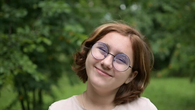 A Teenage Girl With Glasses Makes Funny Faces At The Camera In The Park. Foolishness And Fun. Frames In 4K Format