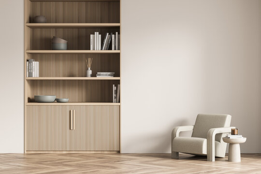 Light beige living room wall with lined bookcase and armchair