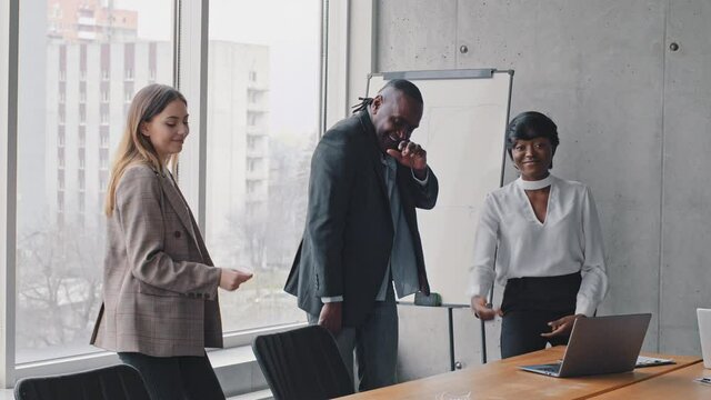 Motivated funny diverse business team people dancing celebrating success in office rejoice with friday weekend, happy friendly multiracial three coworkers group having fun together enjoy victory dance