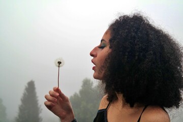 dandelion young brazilian woman afro hair in the cold with fog.