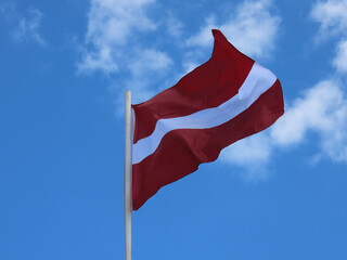 Latvian flag waving in strong wind on a sunny summer day