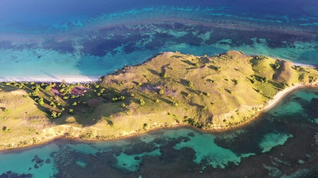 Loho Gebah peninsula in north Komodo Island Indonesia with barrier coral reef, Aerial top view pan right shot