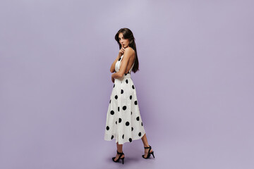 Full length photo of stylish woman with dark hair in midi polka dot light dress and dark shoes...
