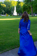 Prom girl spinning in a modern and elegant blue dress. Adorable and fashionable outfit. Beautiful photo from the nature for graduation ceremony