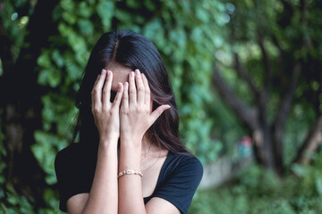 An inconsolable and devastated young woman weeps uncontrollably. Covering face with hands. Loss of...