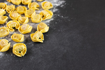 Uncooked tortelloni with mushroom filling on black background,