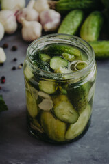 Glass jar with marinated pickled cucumbers in a jar. Selective focus rustic table