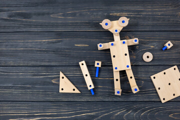 A colorful wooden building kit for children on wood. Set of tools, wooden robot on dark wooden table. Games and tools for kids in preschool or daycare. Natural, eco-friendly toys.