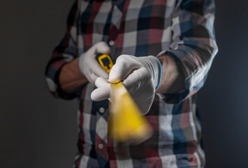 Yellow retractable tape measure tool in hands of repairman, closeup.