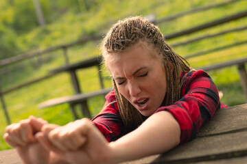 woman stretching arms over a table yawning in the park