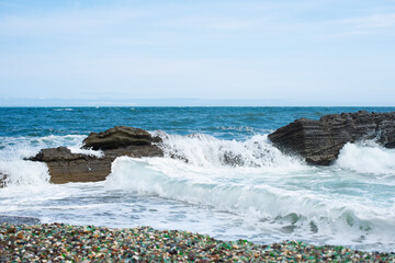 Sea waves on wild stone. Turquoise water, white sea foam and brown rocks, horizontal