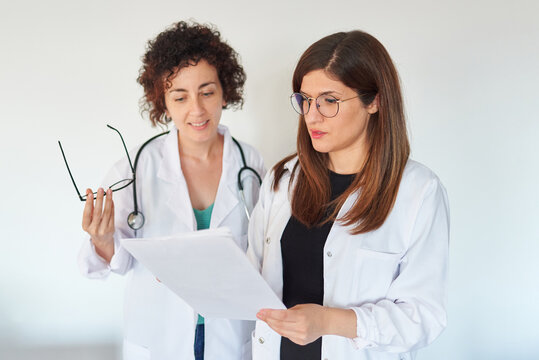 Two female doctors look at documents and discuss a diagnosis