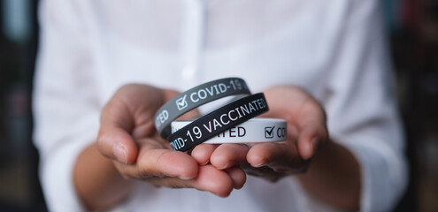 Closeup image of a woman holding Covid-19 vaccination wristband for health care concept