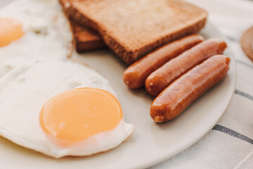 Easy breakfast set of fried eggs toasted bread sausages and tuna spread.