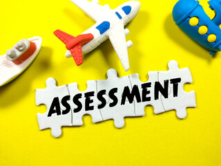 Business concept.Text ASSESSMENT on jigsaw puzzle with toys on a yellow background.
