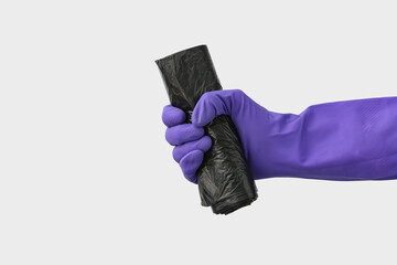 Hand in rubber glove with roll of garbage bag on white background