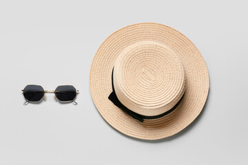 Stylish hat and sunglasses on grey background