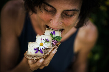 Bird view of a happy woman eating vegan cheese substitute slices on a whole grain bread flowery...
