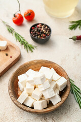 Bowl with delicious pieces of feta cheese on grunge background