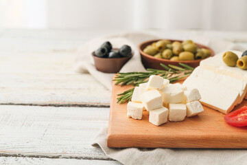 Board with delicious pieces of feta cheese on table