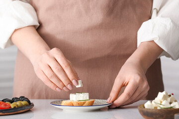 Obraz na płótnie Canvas Woman making sandwich with delicious feta cheese on table
