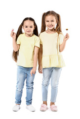Cute little sisters with lollipops on white background