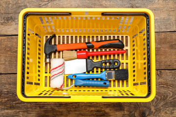 Shopping basket with worker's tools on wooden background