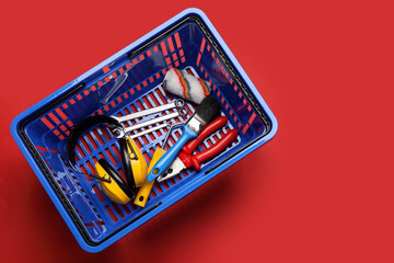 Shopping basket with builder's supplies on color background