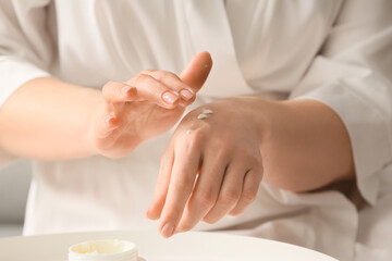 Obraz na płótnie Canvas Woman applying shea butter onto hands at home, closeup