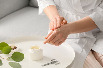 Woman applying shea butter onto hands at home