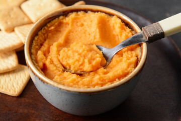 Bowl with tasty carrot hummus on table, closeup