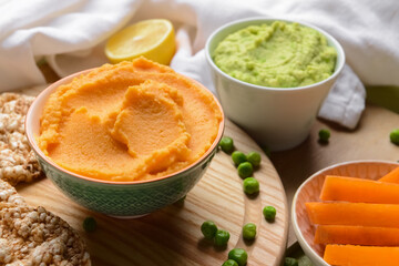 Bowls with tasty hummus and rice crackers on table, closeup