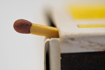 Close up of half of a match with red head out of matchbox with white background