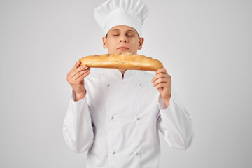 a cook in a chef's uniform holds a loaf of baguette