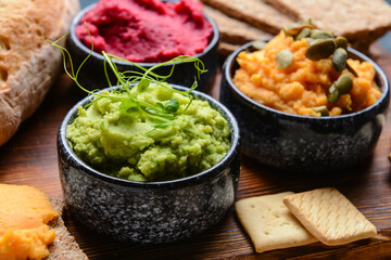Bowls with tasty hummus and crackers on table, closeup