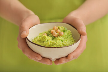 Woman with tasty green pea hummus in bowl, closeup