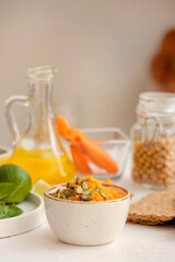 Bowl with tasty carrot hummus on light table, closeup