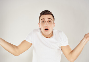 man in white t-shirt throws up his hands emotions light background