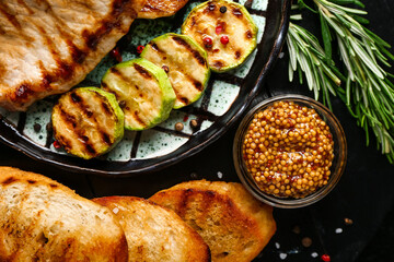 Plate with tasty grilled vegetables, steak and bread on dark background